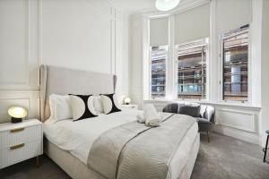 (G3) Grand 2 bed Blythswood Apartment في غلاسكو: غرفة نوم بيضاء بسرير كبير ونوافذ