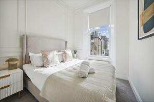 (G3) Grand 2 bed Blythswood Apartment في غلاسكو: غرفة نوم بيضاء مع سرير كبير مع نافذة