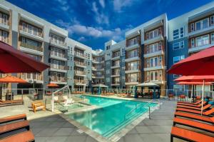 an apartment complex with a swimming pool and red umbrellas at Cozysuites PHX RORO Gym, Pool, Pets, Parking! #9 in Phoenix