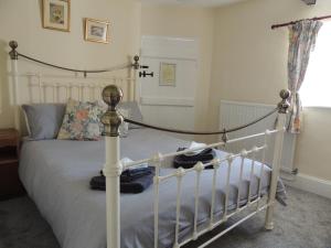 a bedroom with a white bed and a cross on the wall at The Cottage on the Green in Winkleigh