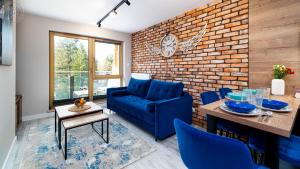 a living room with a blue couch and a brick wall at Apartamenty Good Time- Centrum, blisko wyciągu i szlaków in Szklarska Poręba