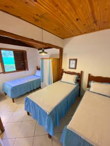 une chambre avec deux lits et un plafond en bois dans l'établissement Pousada Fazenda São Bento, à Alto Paraíso de Goiás