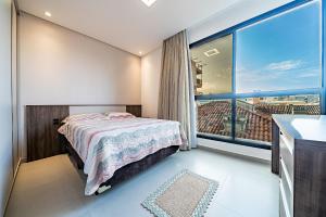 1 dormitorio con cama y ventana grande en 200 - Belíssimo apto Vista Mar sendo 02 suítes, en Bombinhas