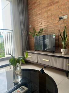 a living room with a television and a brick wall at An Nhiên Vinhome Grand Park 0425 in Ho Chi Minh City
