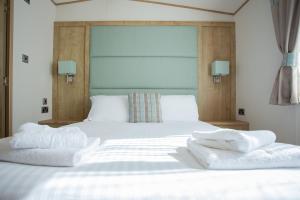 Una cama blanca con dos toallas encima. en St Helens Coastal Resort, en Saint Helens