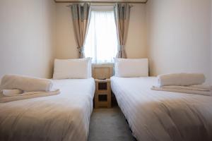 two beds in a small room with a window at St Helens Coastal Resort in Saint Helens