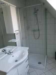 ein weißes Bad mit einer Dusche und einem Waschbecken in der Unterkunft Ferienwohnung Altharlingersiel in Neuharlingersiel