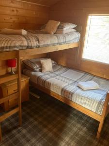 two bunk beds in a cabin with a window at Log Cabin in the City with hot tub in Culloden