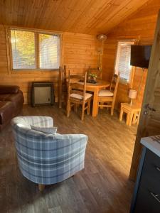 a living room with a table and a couch at Log Cabin in the City with hot tub in Culloden