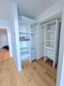 a white closet with white shelves and a wooden floor at Tranquil apartment with panorama view over ocean above 20th floor in Aarhus