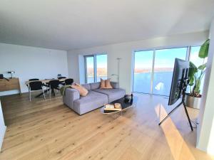 a living room with a couch and a tv and a table at Tranquil apartment with panorama view over ocean above 20th floor in Aarhus