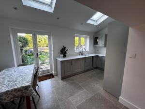a kitchen with a table and a sink and windows at Seven Abbey Lane in Southam