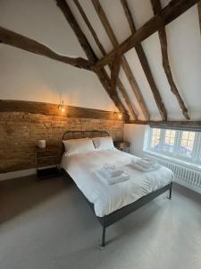 a bedroom with a large white bed with a brick wall at Seven Abbey Lane in Southam