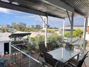 a balcony with tables and chairs and a view of the city at Bulimba Guest House in Brisbane