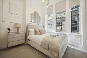a white bedroom with a bed and two windows at (G4) Luxurious 2 Bed Blythswood Flat in Glasgow
