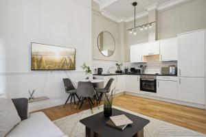 a white living room with a table and a kitchen at (G4) Luxurious 2 Bed Blythswood Flat in Glasgow