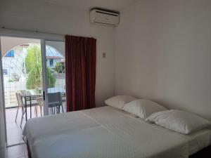 a bedroom with a white bed and a balcony at Maya Apartments in Paramaribo