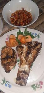 um prato de alimentos com carne e feijão numa mesa em Delima Cottage, Ngurbloat Beach em Ngurblut