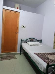 a bedroom with a bed and a wooden door at Full Moon House Tiruvannamalai in Tiruvannāmalai