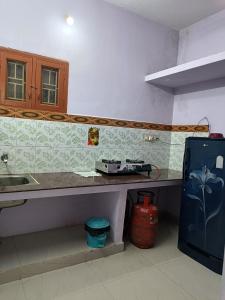 a kitchen with a counter and a sink and a refrigerator at Full Moon House Tiruvannamalai in Tiruvannāmalai