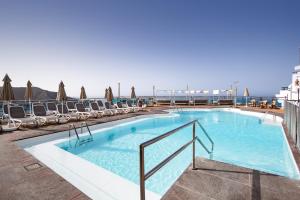 a large swimming pool with lounge chairs and a466 at Servatur JB - Adults Only in Puerto Rico de Gran Canaria