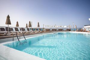 a large swimming pool with chairs and umbrellas at Servatur JB - Adults Only in Puerto Rico de Gran Canaria