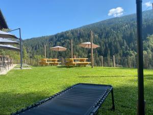 a bench in a field with tables and umbrellas at Arriach Apartments in Arriach
