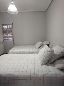 a white bedroom with two beds and a window at CASA ANTONIO Y GABI Ruta de los dinosaurios in Igea