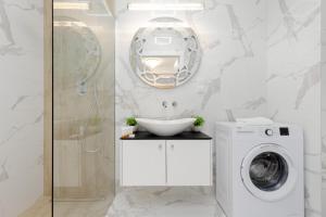 a bathroom with a washing machine and a mirror at Warsaw Sarmacka Apartment with Gym, Sauna and Parking by Renters in Warsaw