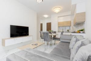 un soggiorno con divano, TV e tavolo di Warsaw Sarmacka Apartment with Gym, Sauna and Parking by Renters a Varsavia