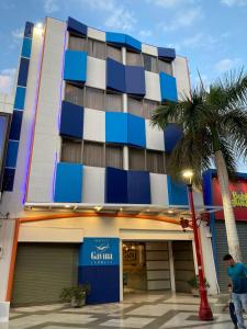 a man walking in front of a building with a palm tree at Hotel Gavina Express in Arica