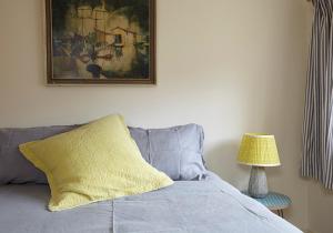 a bed with a yellow pillow and a picture on the wall at The Squeak at Moor Farm in Godshill