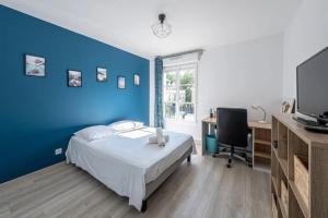 een slaapkamer met een blauwe muur en een bed en een bureau bij F2 Cozy Pour 4 Proche Disneyland - Fairytale Factory in Villeneuve-Saint-Denis