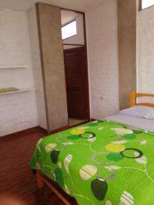 a bedroom with a green blanket on a bed at CASA VILLA SOL in Tumbes