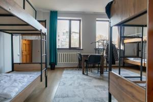 a room with bunk beds and a dining room with a table at Almaty Backpackers in Almaty