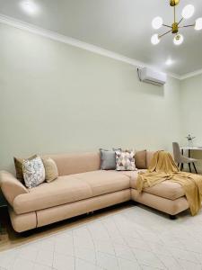 un sofá marrón en una sala de estar con techo en ЖК Homeland EXPO 2 комн, en Taldykolʼ
