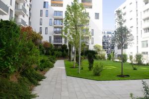 an apartment garden with trees and grass in front of a building at MH Residence in Cluj-Napoca