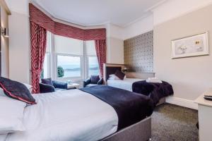 a hotel room with two beds and a window at Lauriston & Lawton Court Hotel in Llandudno