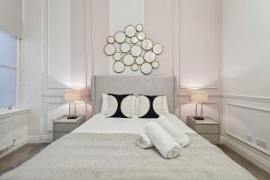 a white bedroom with a large bed with two lamps at (G5) Grand 1 bed Blythswood Apartment in Glasgow