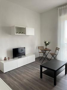 uma sala de estar branca com uma televisão e uma mesa em Exphome em Novate Milanese