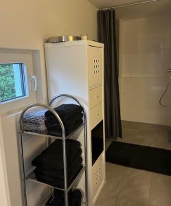 baño con ducha y estante con toallas en ruhig wohnen im kleinen Bungalow im Süden von Berlin, en Teltow