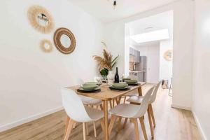 une salle à manger avec une table en bois et des chaises blanches dans l'établissement Appartement RDC Mairie de Marcq, à Marcq-en-Barœul