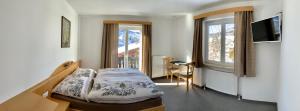 a bedroom with a bed and a desk and window at Haus Seiwald, Haid 18 in Wagrain
