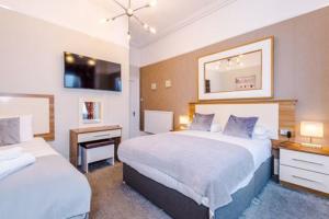 a hotel room with two beds and a desk at Lauriston & Lawton Court Hotel in Llandudno