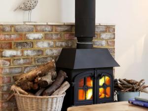 a brick fireplace with a wood burning stove at Mill Barn in Chailey