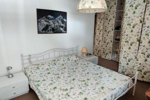 una camera da letto con un letto con copriletto floreale di Casa Madesimo - Impianto sciistico e Parcheggio a Madesimo