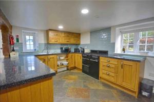a large kitchen with wooden cabinets and black appliances at Dale Cottage 18th Century Country Cottage, 111 Barnston road in Heswall