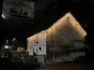 an old stone building with lights on it at night at Dale Cottage 18th Century Country Cottage, 111 Barnston road in Heswall
