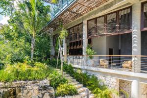 a house with a balcony with chairs and trees at Divine 2BR Tulum on Cenote Gym in Tulum