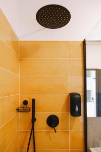 a bathroom with a yellow tile wall with a speaker at Cà de Mâ Ω Sea Front Apartment in Genoa